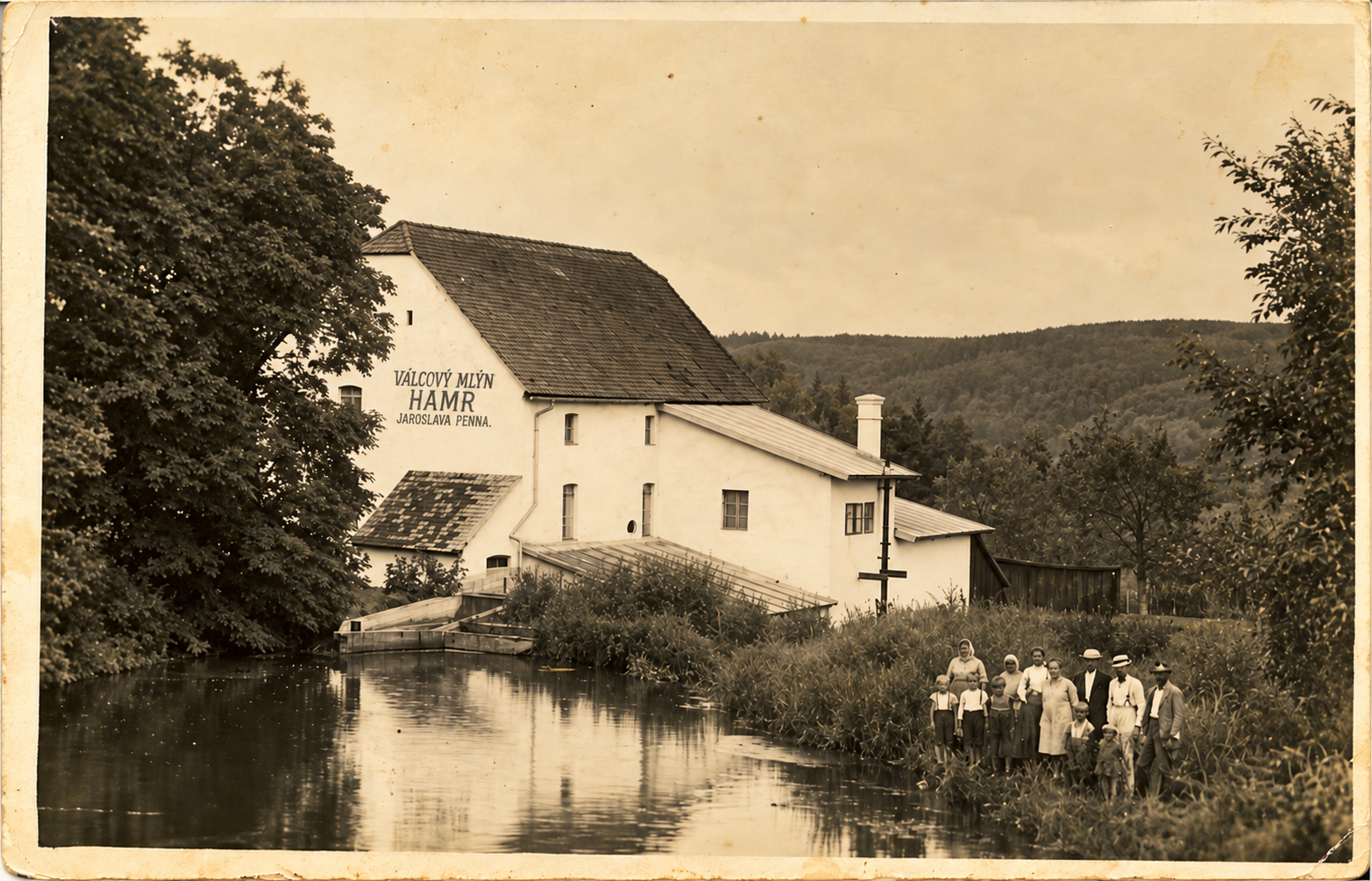 Stará černobílá fotografie budovy mlýna, před ní stojí skupina lidí v historických šatech.